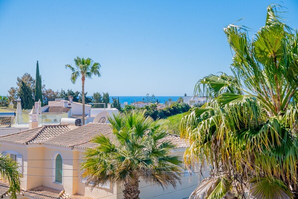 A coastal view with a building featuring terracotta roofs, palm trees, and a clear blue sky. - Casa do Livramento - Fabulous 3 bedroom villa with games room (Carvoeiro)