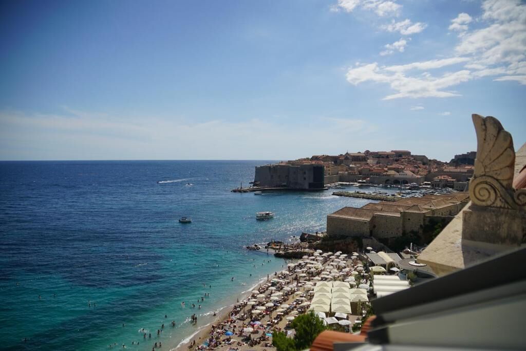 A coastal town with a beach, a historic fort, and a clear sky.