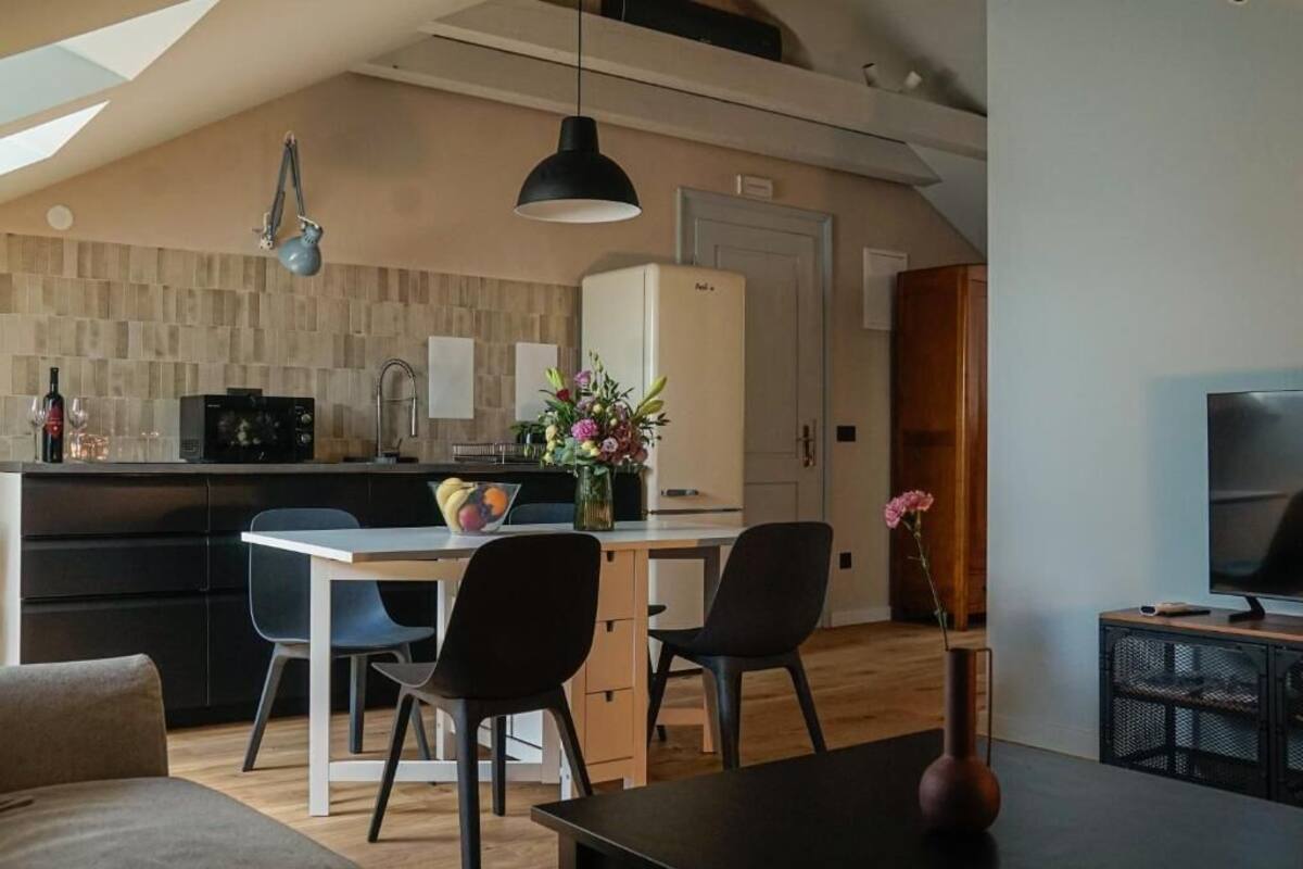 Una cocina moderna con zona de comedor, televisor y techo de madera.