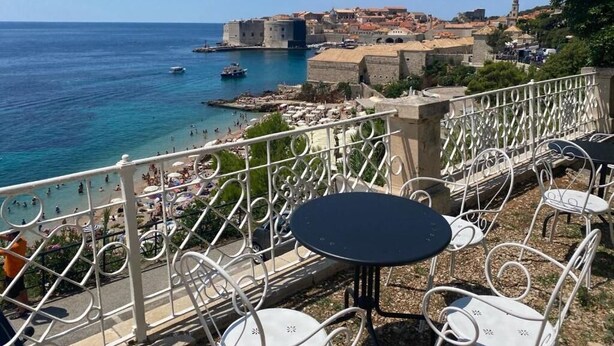 A seaside terrace with outdoor seating, overlooking a historic town and the sea. - Onyx Apartments 2&4 (Dubrovnik)