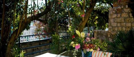 Une table avec un vase de fleurs, une chaise et un mur de pierre en arrière-plan.