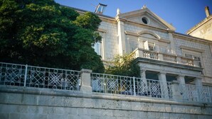 A classical building with a stone facade, a balcony with ornate metal railings, and a clear sky. - Onyx Apartments 2&4 (Dubrovnik)