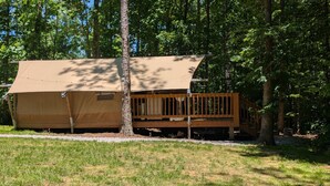 Une petite cabane en bois d’un seul étage, dotée d’une terrasse et entourée d’arbres.