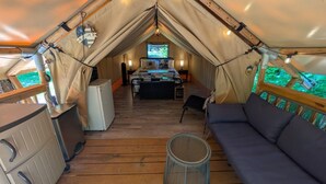 Un hébergement en tente comprenant un coin cuisine, un lit, un espace salon et une vue sur l’extérieur.