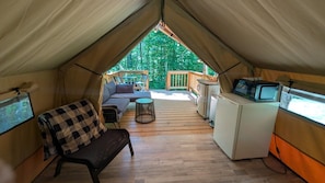 Overnatningstelt med sofa, lille bord, fjernsyn og køleskab.