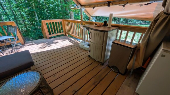 A wooden deck with a grill, a small refrigerator, and a seating area with a table and chairs.