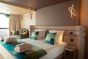 A hotel room with a large bed, a round wall light, and a view of the outdoors. - Fahrenheit Seven Les Menuires (Les Belleville)