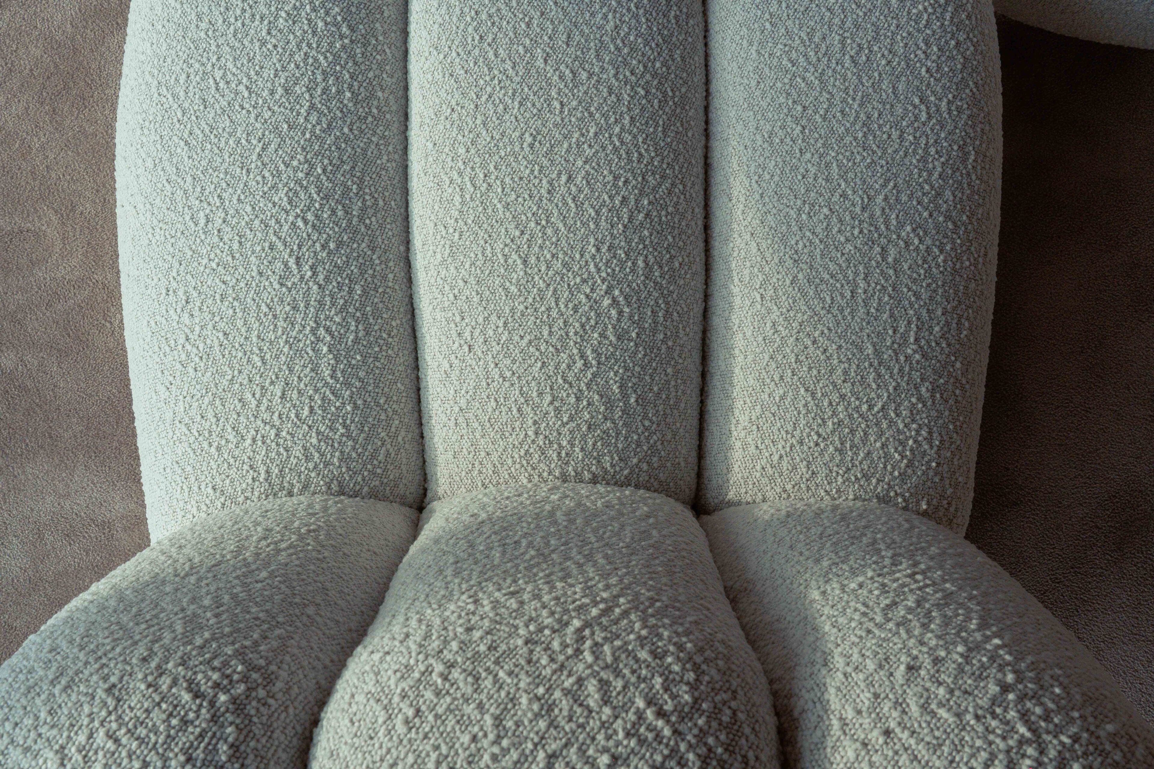 Gros plan d’un fauteuil à l’assise rembourrée et au dossier haut, dont la texture est visible.
