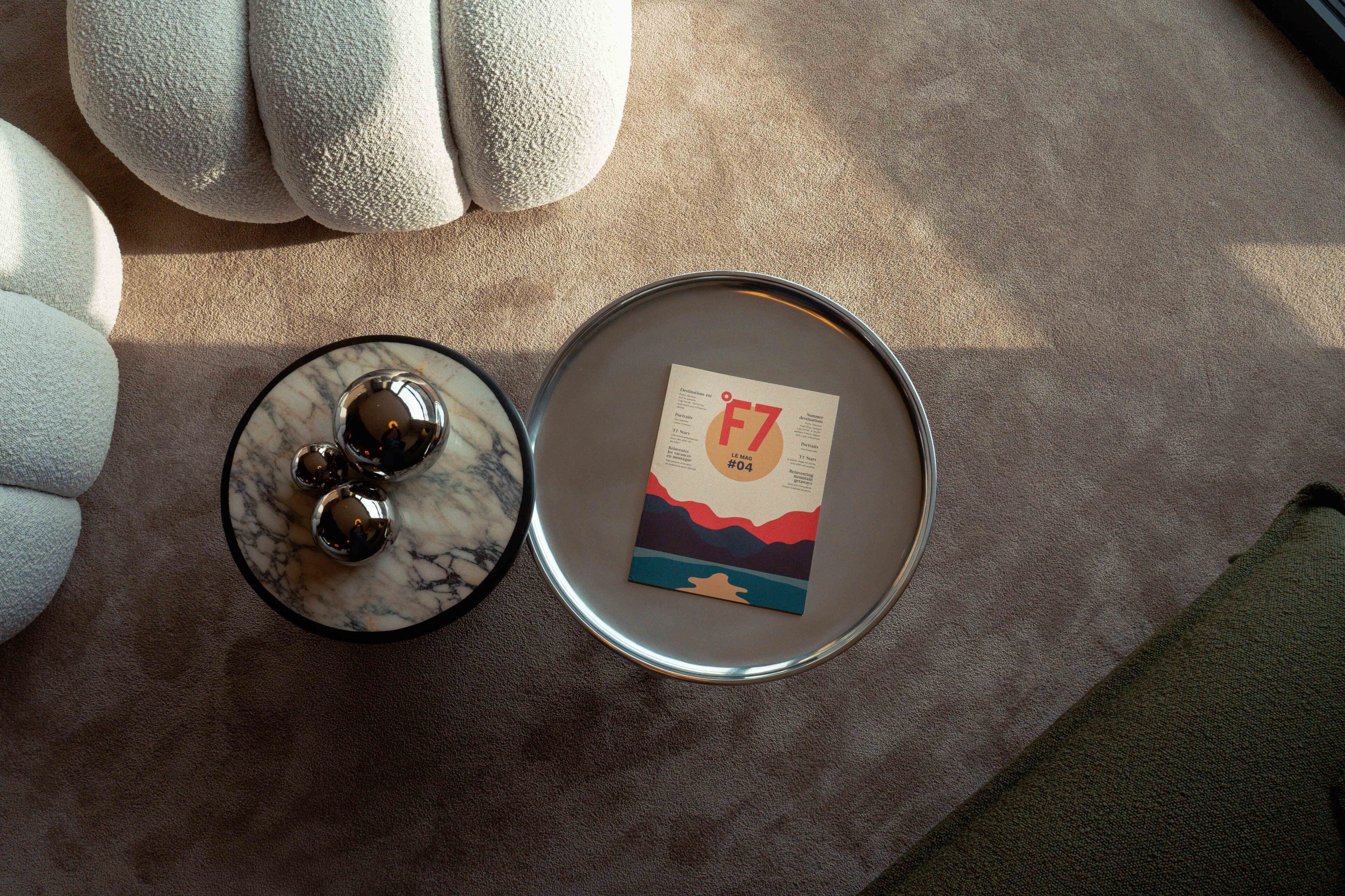 Une table ronde avec un plateau en marbre, une bougie et une carte décorée d’un motif de coucher de soleil.