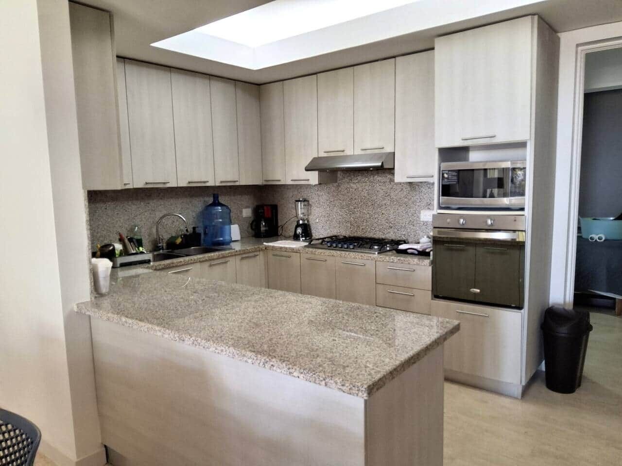 Una cocina moderna con encimeras de granito, electrodomésticos de acero inoxidable y armarios de madera clara.
