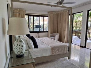 A bedroom with a bed, a lamp, a chair, a ceiling fan, and a view of the outdoors. - Gorgeous large condo, quiet beachfront complex (Las Terrenas)