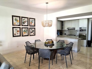 A modern dining area with a glass table and chairs, surrounded by framed botanical prints. - Gorgeous large condo, quiet beachfront complex (Las Terrenas)