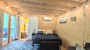 Een gezellige slaapkamer met een bed, nachtkastjes, een bankje, een raam met gordijnen en een deur naar buiten.