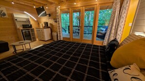 Een gezellig houten kamer met een groot bed, een kleine kitchenette en een schuifdeur naar een terras.