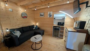Een gezellige kamer met een bank, een tafeltje, een magnetron en een televisie.