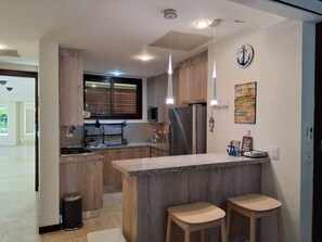Eine moderne Küche mit Holzschränken, Edelstahlgeräten und einer Bar mit Hockern.