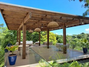 Eine Terrasse im Freien mit einer Holz-Pergola, Korbmöbeln und Blumentöpfen.