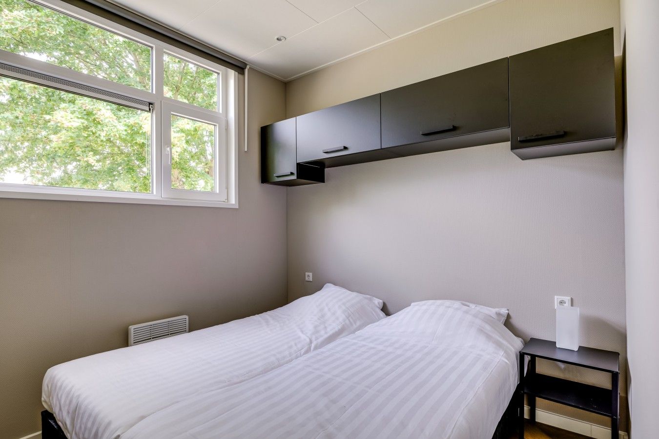 Une chambre à coucher avec un lit, une fenêtre et des placards intégrés.