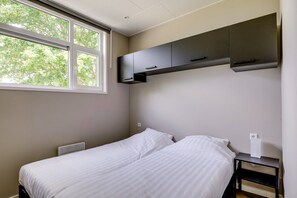 Ein Schlafzimmer mit einem Bett, einem Fenster und Einbauschränken.