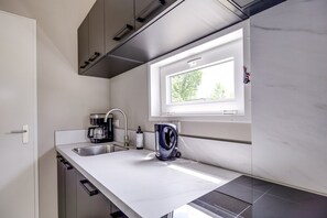Una cocina moderna con ventana integrada, cafetera y hervidor sobre la encimera.