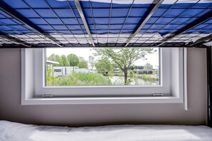 Um quarto com uma cama, uma janela e vista para um prédio e árvores.