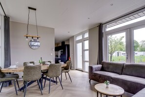 Un comedor moderno con una mesa y sillas de madera, un sofá y una mesa redonda de centro.