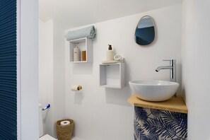 A bathroom with a white sink, a mirror, and shelves with toiletries. - Room with Néron View in the Heart of Chartreuse (Quaix-en-Chartreuse)
