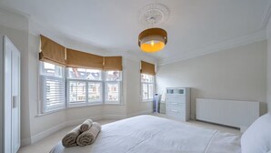 Ein Schlafzimmer mit einem großen Bett, einem Heizkörper, einem Kleiderschrank und einem Fenster mit Jalousien.