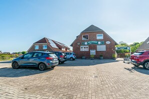A hotel with a traditional brick facade, solar panels on the roof, and a sign indicating it's a hotel. There are cars parked in front. - Room 'Zimmer 2' with Shared Terrace and Wi-Fi (Dornum)
