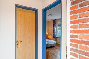 A room with a bed, a window with curtains, and a door with a blue frame. - Room 'Zimmer 2' with Shared Terrace and Wi-Fi (Dornum)