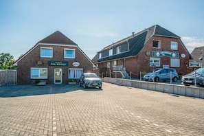 A brick building with a sign for Zum Vikinger Hotel. There are two cars parked in front.