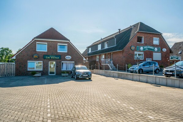 A brick building with a sign for Zum Vikinger Hotel. There are two cars parked in front.