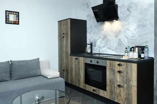 A modern kitchen with a built-in oven, a coffee maker, and a flat-screen TV mounted above the counter.