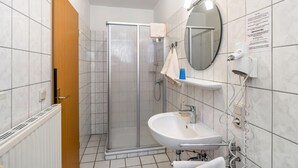 A modern bathroom with a shower, sink, and mirror. - Room 'Doppelzimmer 2 Gästehaus' with Shared Terrace and Wi-Fi (Dornum)