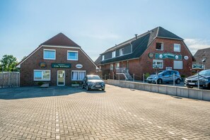 Een bakstenen gebouw met een bord waarop 'Zum Vikinger Hotel' en 'Zum Vikinger Eingang' staat. Er zijn auto's geparkeerd voor het gebouw en een verharde oprit naar de ingang.