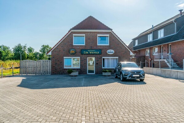A two-story brick building with a sign reading 'Zum Wiking' and a parked car in front.