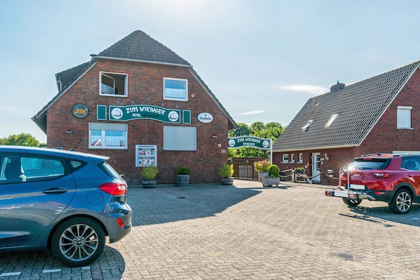A brick building with signage for Zum Vikinger Hotel and Krombacher.