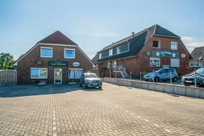 A brick building with a sign for Zum Vikinger Hotel. There are two cars parked in front.