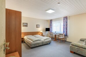A hotel room with a bed, a desk, a chair, a TV, and a window with curtains. - Room 'Doppelzimmer 3 Haupthaus' with Shared Terrace and Wi-Fi (Dornum)