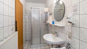 Ein Badezimmer mit Dusche, Waschbecken und Spiegel.