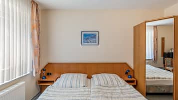 A hotel room with a double bed, two bedside tables with lamps, a small picture on the wall, and a window with curtains.