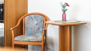 A wooden chair with a patterned cushion and a small round table with a vase of flowers. - Room 'Doppelzimmer 4 Gästehaus' with Shared Terrace and Wi-Fi (Dornum)