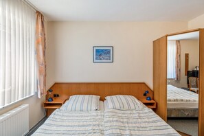 A hotel room with a double bed, two bedside tables with lamps, a framed picture on the wall, and a window with curtains.