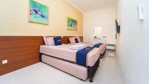 Ein Hotelzimmer mit zwei Betten, einem Holzkopfende, einer weißen Wand und zwei Bildern.
