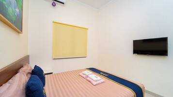 A hotel room with a bed, a flat-screen TV, an air conditioning unit, and a painting on the wall.