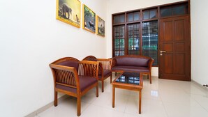 Ein Zimmer mit einer Sofagarnitur, einem Glastisch und einer Holztür mit Glaseinlagen.