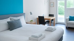 A modern hotel room with a large bed, a desk, and a chair.