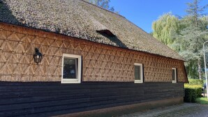 A building with a thatched roof, wooden siding, and two windows with white frames.