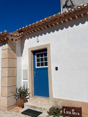 Un bâtiment avec une porte bleue, des murs blancs et un toit recouvert de tuiles.