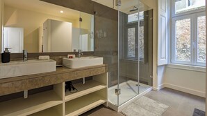 A modern bathroom with two sinks, a glass-enclosed shower, and a large mirror. - MyPlaceLisbon - Luxury Trindade II (Lisboa)
